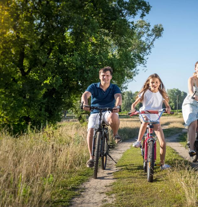 Familie fährt auf einem Landweg Fahrrad.